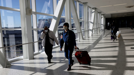 Air travelers wearing protective face masks, amid the coronavirus disease (COVID-19) pandemic, walk at JetBlue Terminal 5 at JFK International Airport in New York, U.S., November 16, 2021. REUTERS/ Shannon Stapleton/File Photo