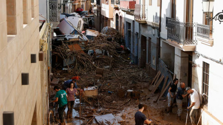 People work to clear a street covered in mud with cars piled up after torrential rain caused flooding in Paiporta, Spain October 31, 2024. REUTERS/Eva Manez