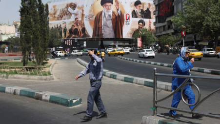 People walk past a billboard featuring images of Iran's late Supreme Leader Ayatollah Ali Khamenei in Tehran, Iran, July 13, 2026.