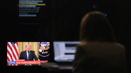 A journalist works as a screen displays US President Donald Trump speaking about election security during an address to the nation from the East Room of the White House, in Washington, DC. Photo: Reuters