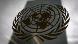 The United Nations headquarters building is pictured though a window with the UN logo in the foreground in the Manhattan borough of New York August 15, 2014/ Reuters 