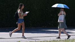 People use umbrellas and fans to protect themselves from high temperatures in Munich, Germany, 26 June 2026. REUTERS/Angelika Warmuth